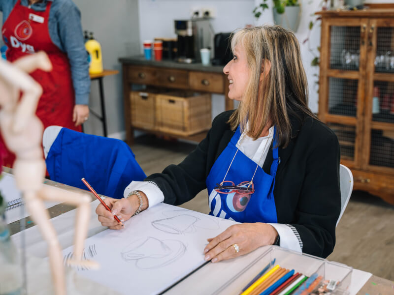 A lady learns how to draw from an expert in an art class.